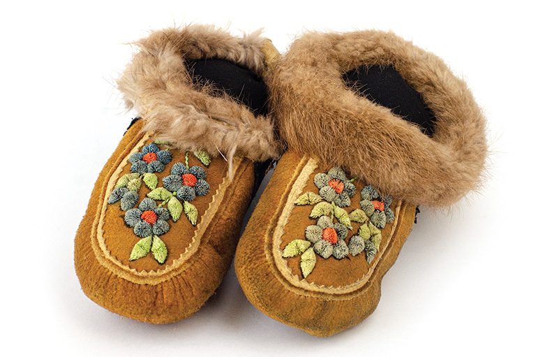 Brown animal skin moccasins with blue flowers on the front and fur trim around the ankles.
Artifacts from the Manitoba Museum (HBC 42-26)